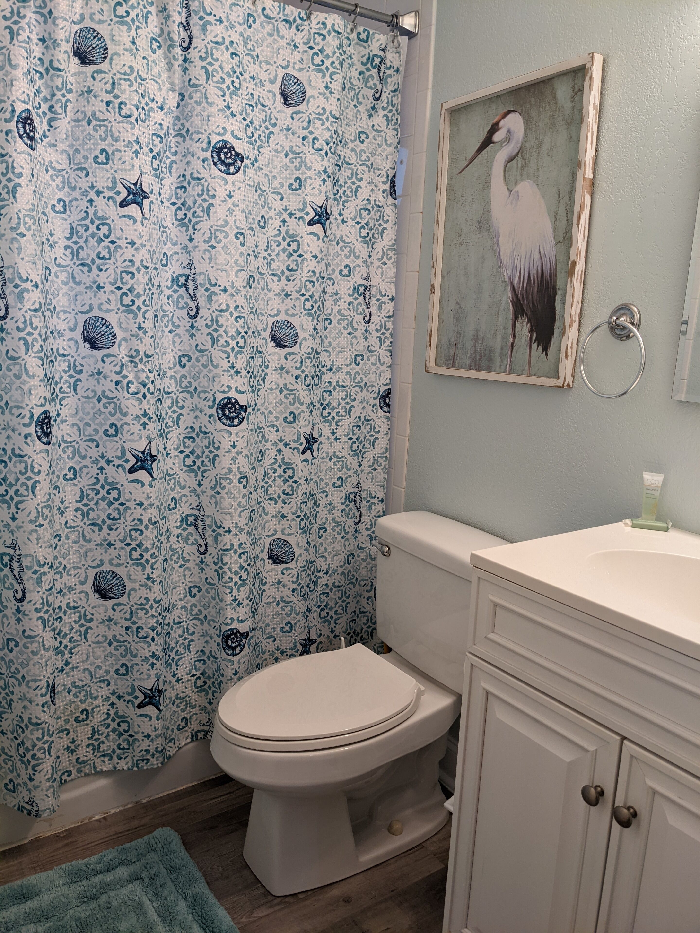 A bathroom with a toilet, a sink, and a shower curtain with a sea-themed pattern.