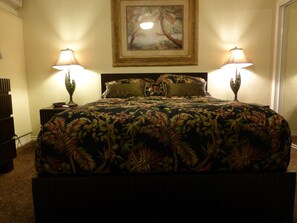 A bed with a floral bedspread, two bedside lamps, and a framed picture on the wall.