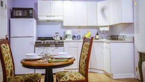 A compact kitchen with white cabinets, a microwave, a stove, and a dining table with chairs. - Secluded, Sunny Studio.  Fully Private: entrance, bath, bedroom, kitchen & Patio (Valley Stream)