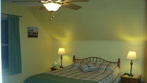 Una camera da letto con un letto, due lampade da comodino, una ventola a soffitto e una finestra con tende.