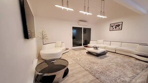 Un saló modern amb un sofà blanc, una taula de centre rodona i una catifes mullada.