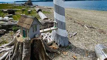 Un phare aux motifs rayés, situé sur une côte rocheuse, avec un petit bâtiment à proximité.