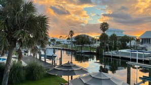 A marina with boats docked, a grassy area with umbrellas, and houses in the background. - Perdido Key Waterfront Home with boat dock, canal, Gulf right across the street (Pensacola)