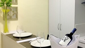 A dining area with a table set for two, a vase with flowers, and a bottle of wine in a bucket. - Luxury Palm Beach Suite 5mins Away Walkable from the Beach & Marriott Hotel (Aruba)