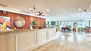 A hotel reception area with a counter, a piano, and a seating area with tables and chairs. - Amazing Diamond Head and Ocean Views, Prime Location-Free High Speed Wifi (Honolulu)