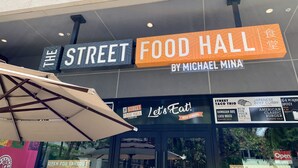 The exterior of The Street Food Hall by Michael Mina, featuring a signboard with various food options and a 'Let's Eat!' banner. - Amazing Diamond Head and Ocean Views, Prime Location-Free High Speed Wifi (Honolulu)