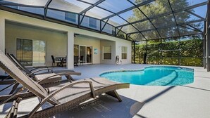 A modern house with a glass-enclosed patio, a swimming pool, and outdoor furniture. - Near Disney, Upscale 5 BR 2 Story Pool Home w/ game room (Davenport)