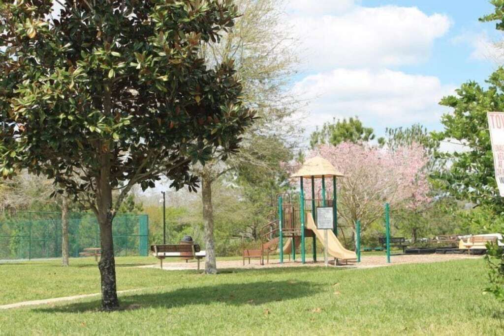 A park with a playground, benches, and a tree.