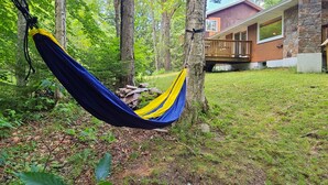 A hammock hanging between trees in a forested area with a house in the background. - Spacious 6BR - 5BA Ski Home on Pico Mountain - Minutes to Killington Mountain (Killington)