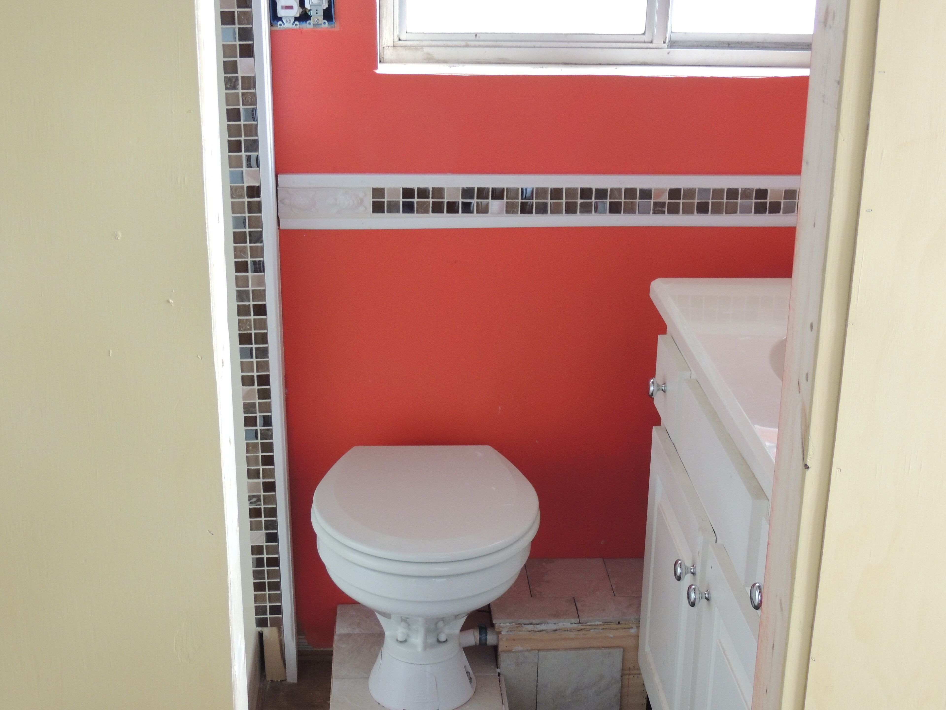 A small bathroom with a white toilet, a white sink, and a red wall.