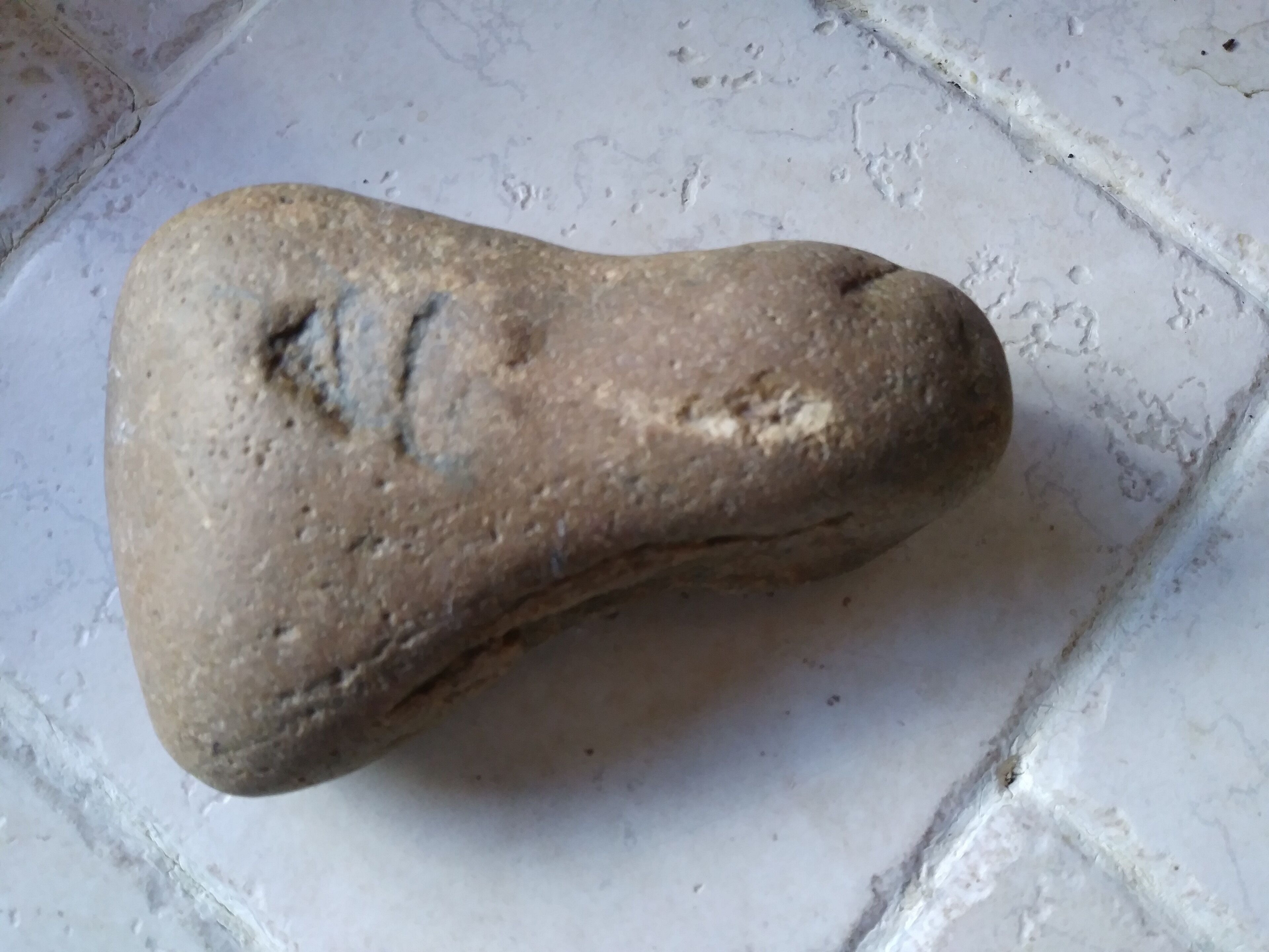 A stone with a carved symbol on a tiled surface.