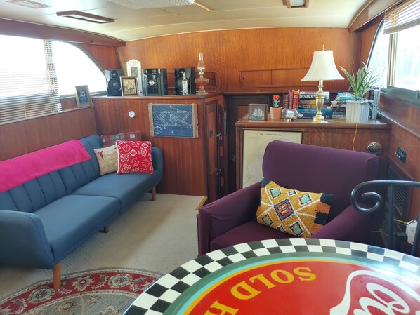 Un espacio habitable compacto con un sofá azul, un sillón morado y una mesita con borde a cuadros.