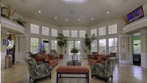 A spacious lobby with a high ceiling, large windows, and a central seating area with sofas and a bench. - Luxury Pool Home Steps to Disney, 2 Master Suites, Gated, Game Rm, BBQ Free WiFi (Kissimmee)