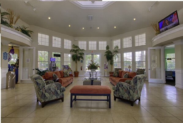 A spacious lobby with a high ceiling, large windows, and a central seating area with sofas and a bench. - Luxury Pool Home Steps to Disney, 2 Master Suites, Gated, Game Rm, BBQ Free WiFi (Kissimmee)