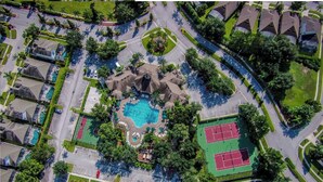 An aerial view of a residential area with a swimming pool, tennis courts, and a landscaped park area. - Luxury Pool Home Steps to Disney, 2 Master Suites, Gated, Game Rm, BBQ Free WiFi (Kissimmee)