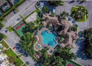 Vista aérea de um resort com piscina central, cercada por palmeiras e áreas sombreadas.
