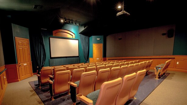 A theater with rows of seats, a screen, and a stage area. - Luxury Pool Home Steps to Disney, 2 Master Suites, Gated, Game Rm, BBQ Free WiFi (Kissimmee)