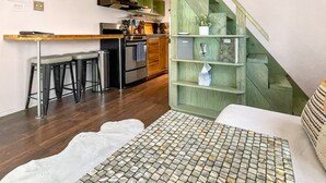 Een compacte keuken met een houten aanrecht, een inbouwoven en een groene trap.