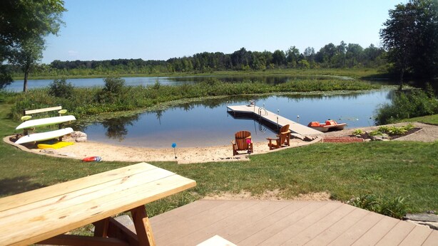 Un espace de pique-nique au bord du lac, doté d’une terrasse en bois, d’une table de pique-nique et de plusieurs chaises Adirondack.