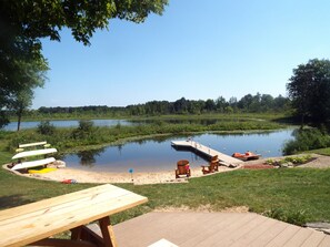 Un espace de pique-nique au bord du lac, doté d’une terrasse en bois, d’une table de pique-nique et de plusieurs chaises Adirondack.