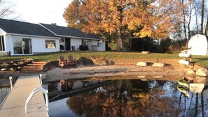 Une maison dotée d’une cour arrière comprenant une piscine, un quai et un espace jardin aménagé avec des chaises.