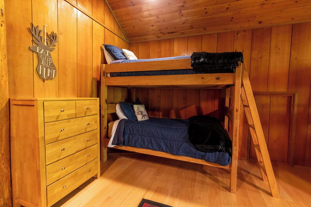 Une chambre avec un lit superposé, une commode en bois et un panneau décoratif mural.