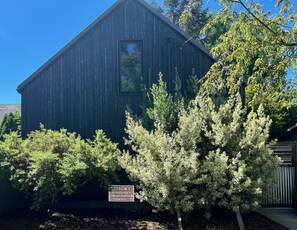 Un bâtiment en bois sombre, avec une fenêtre et une enseigne devant.