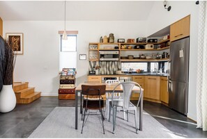 Une cuisine moderne avec des meubles en bois, un réfrigérateur en acier inoxydable et un coin repas comprenant une table et des chaises.