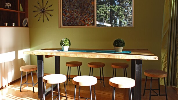 A kitchen with a wooden table, bar stools, and two potted plants. - Cozy Kirkland Finn Hill Home (Kirkland)