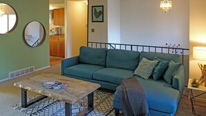 A living room with a green sofa, a coffee table, and a chandelier. - Cozy Kirkland Finn Hill Home (Kirkland)