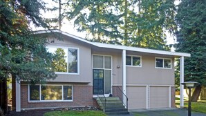 A two-story house with a garage, a front porch, and a staircase leading to the entrance. - Cozy Kirkland Finn Hill Home (Kirkland)