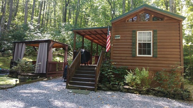 A wooden cabin with a porch and a staircase leading to the entrance.