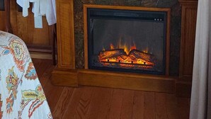A cozy room with a fireplace, a television, and a bed with a floral bedspread.