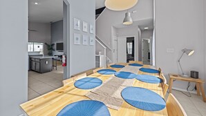 A modern dining area with a long wooden table, blue cushions, and a woven mat. - Recently renovated 5BR/4BA villa with private pool&spa located in Hampton Lakes. (Davenport)