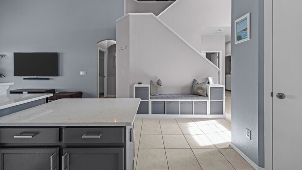 A modern kitchen with a large island, a built-in bench with cushions, and a staircase leading to an upper level. - Recently renovated 5BR/4BA villa with private pool&spa located in Hampton Lakes. (Davenport)