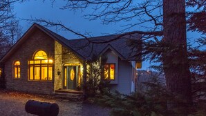 A stone house with a large front door and two windows, surrounded by trees.