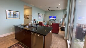 Una cucina moderna con isola centrale, una zona pranzo con una sedia rossa e una TV sullo sfondo.
