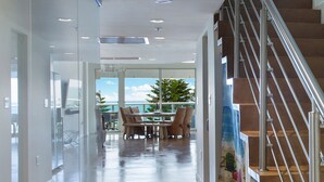 Un interior moderno con un vidrio que da a un comedor con vista al océano.
