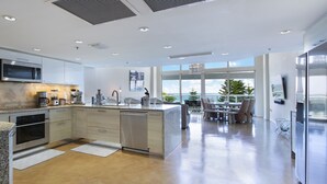 Una cocina moderna con electrodomésticos de acero inoxidable, una zona de comedor con vistas y una isla grande.