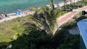 Una playa con gente, una tienda de campaña y un sendero que lleva al agua.