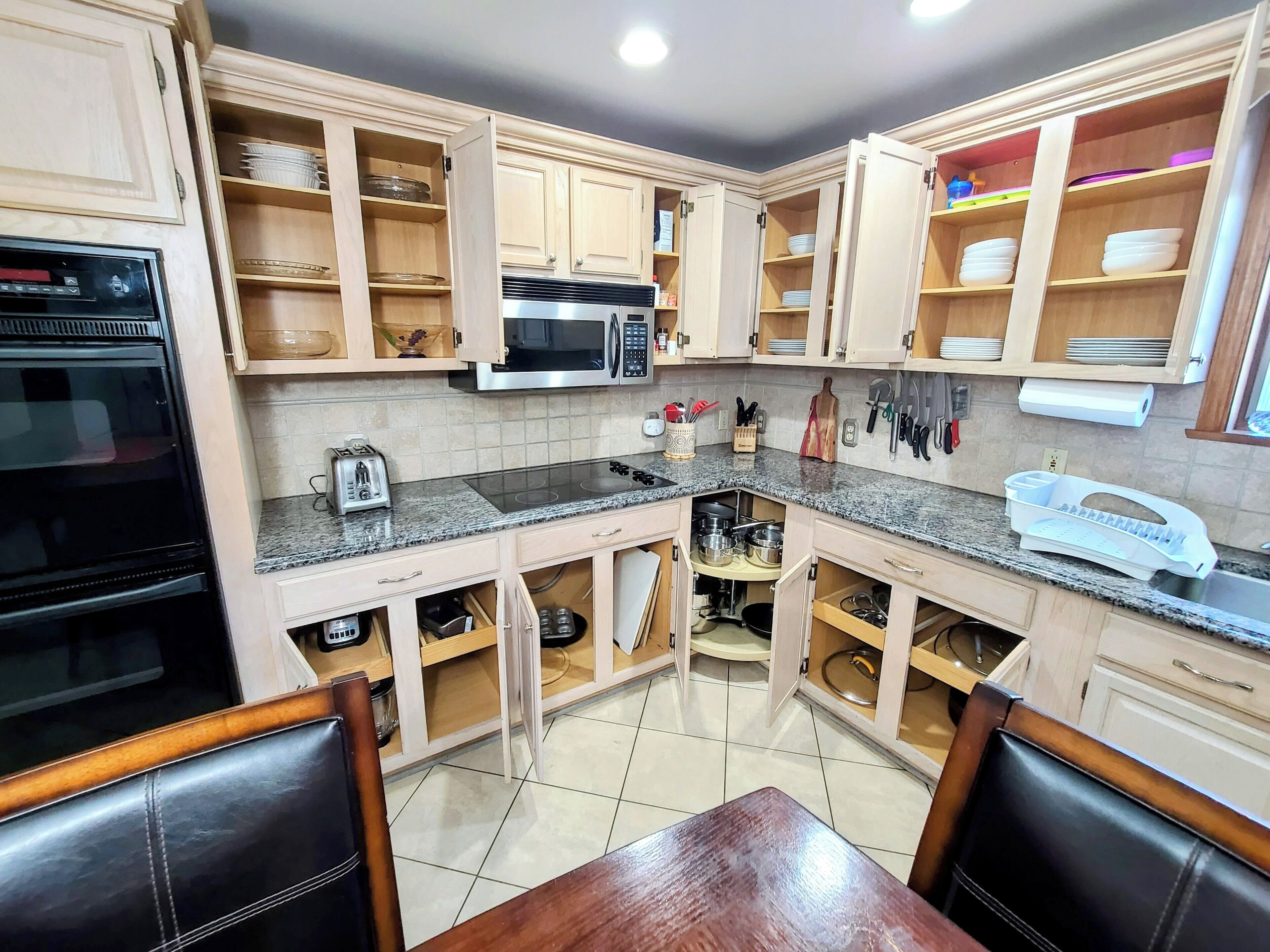 A kitchen with wooden cabinets, a microwave, a stove, and a dining area with a table and chairs.