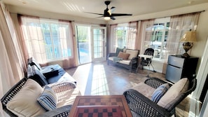 A spacious living area with a ceiling fan, a sofa, a dining table, and a baby rocker. - Spacious Family Retreat on 7.5 Private Acres Sleeps 10+ Pool/Hot Tub/Sauna/GR (East Stroudsburg)
