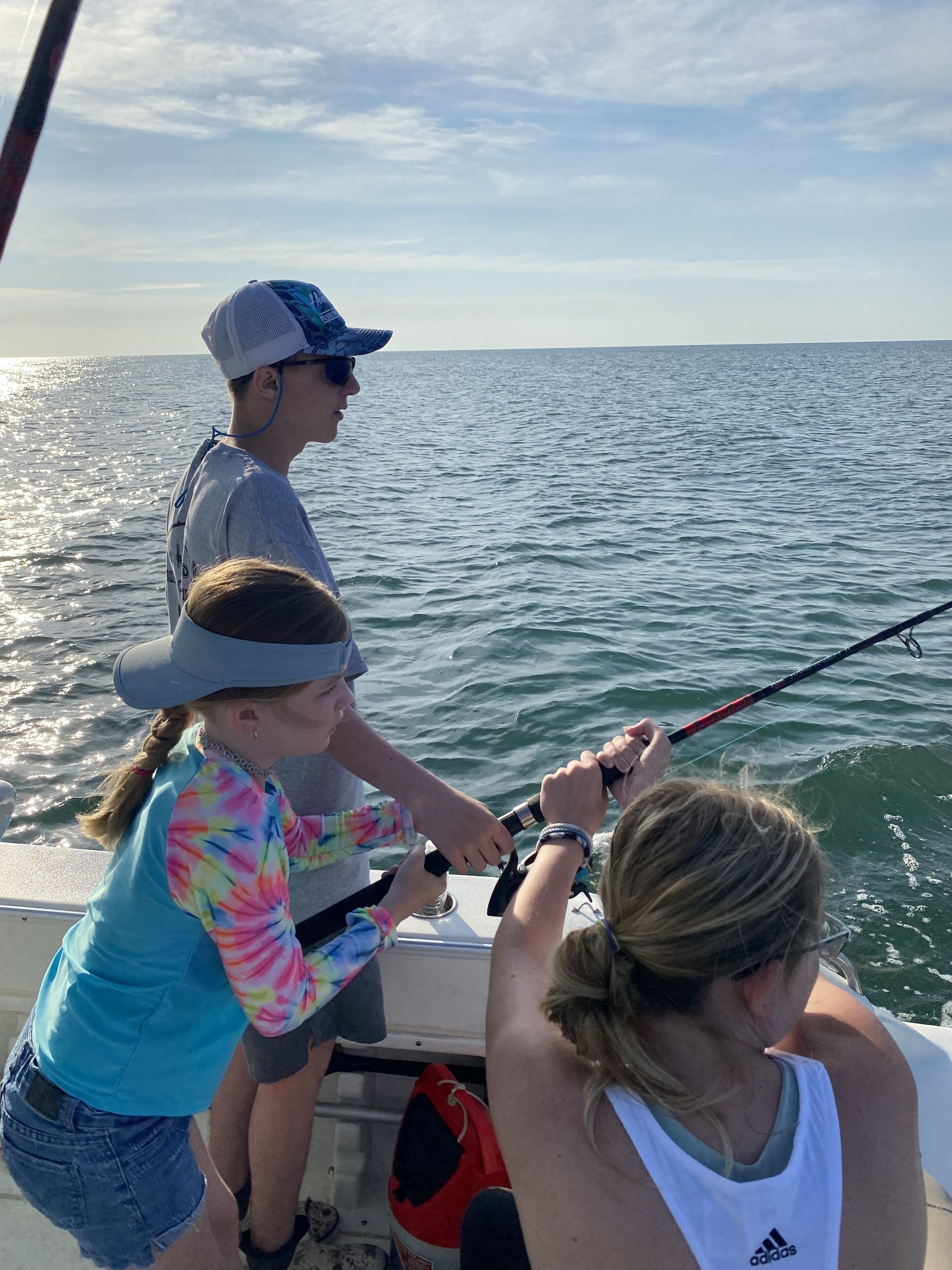 A boat with two people fishing, a clear view of the water, and a distant horizon.