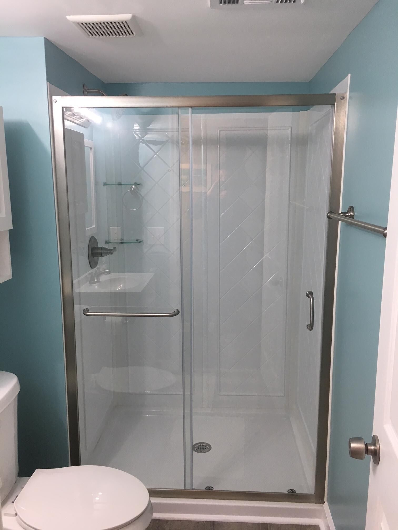 A glass-enclosed shower stall with a toilet and sink to the left.