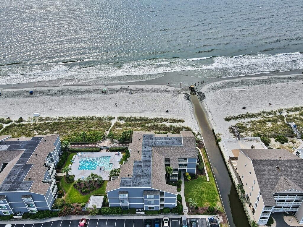 Un hôtel situé sur la côte, doté d’une piscine, d’une plage et d’une route menant à la plage.