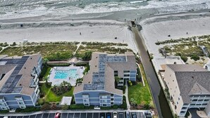 Un hotel frente al mar con piscina, playa y un camino que lleva a la playa.