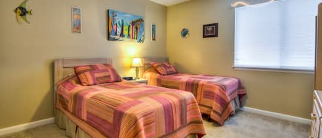 A bedroom with two beds, a ceiling fan, and a window with blinds.
