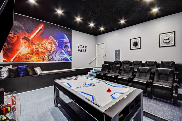 Une salle de cinéma avec une affiche de Star Wars, des sièges confortables, un comptoir de vente de collations et un écran de projection.
