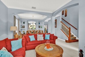 Un salon avec un canapé rouge, une table basse et un escalier.