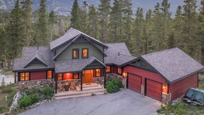 A large, multi-story house with a stone foundation, a garage, and a covered porch.